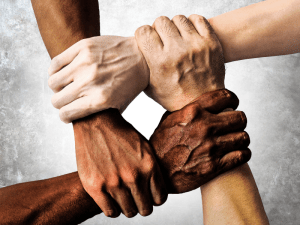 Four hands of differing skin tones hold onto each other